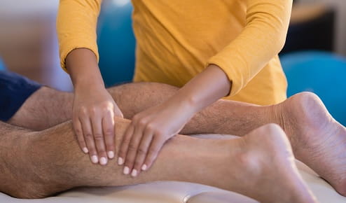 Woman Giving a Man a Leg Massage at Home A Woman Giving a Man a Leg Massage at Home